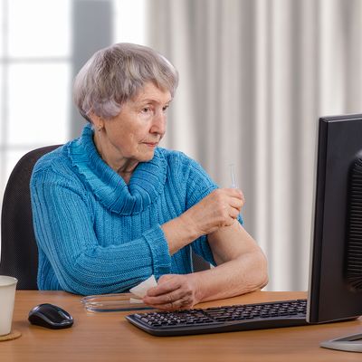 Ältere Frau sitzt vor einem Computer mit Webcam
